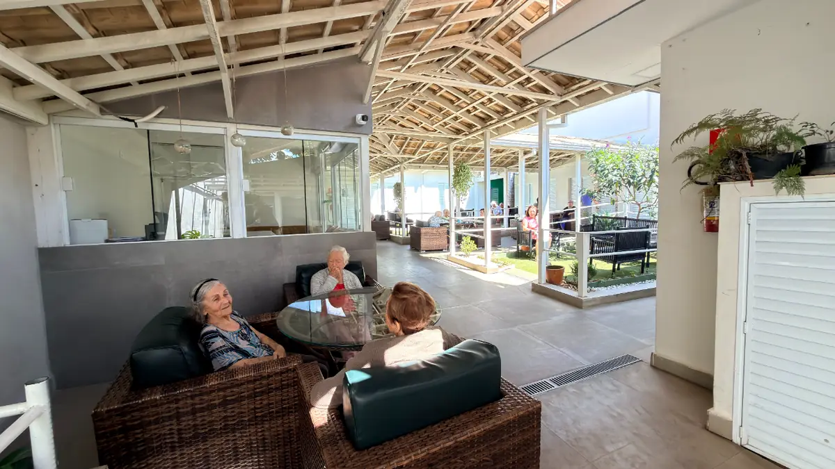 Área de convivência com sofás externos e residentes conversando no Residencial Veneza
