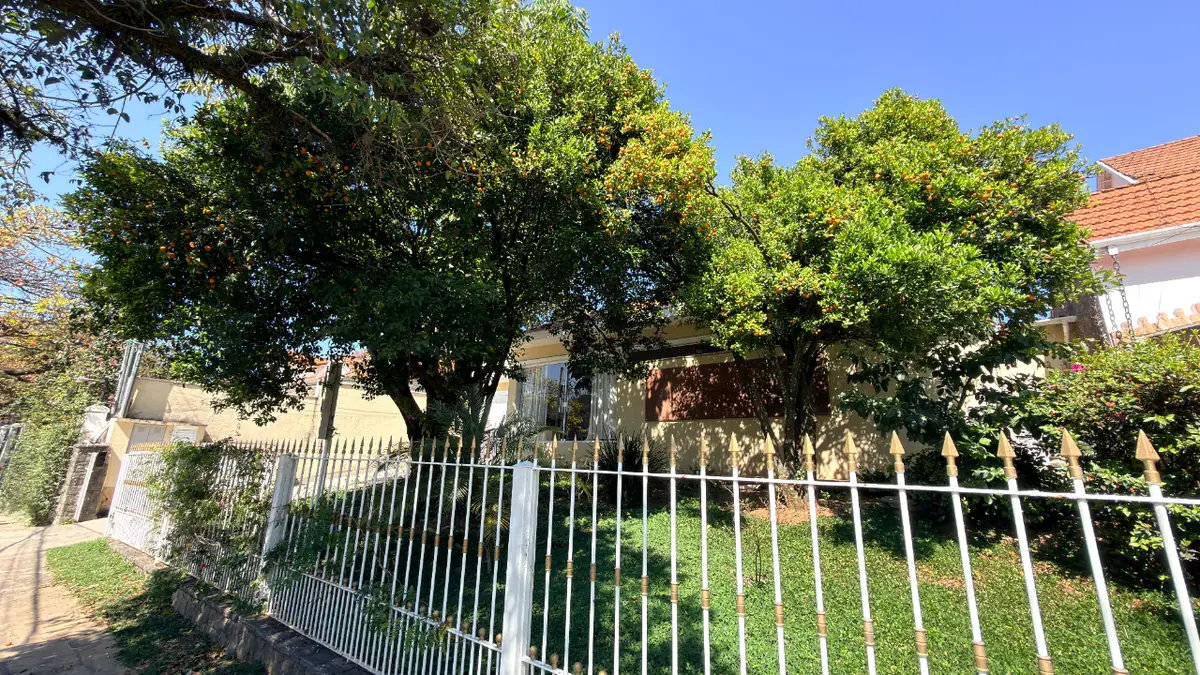Jardim frontal arborizado com grade branca do Residencial Veneza no