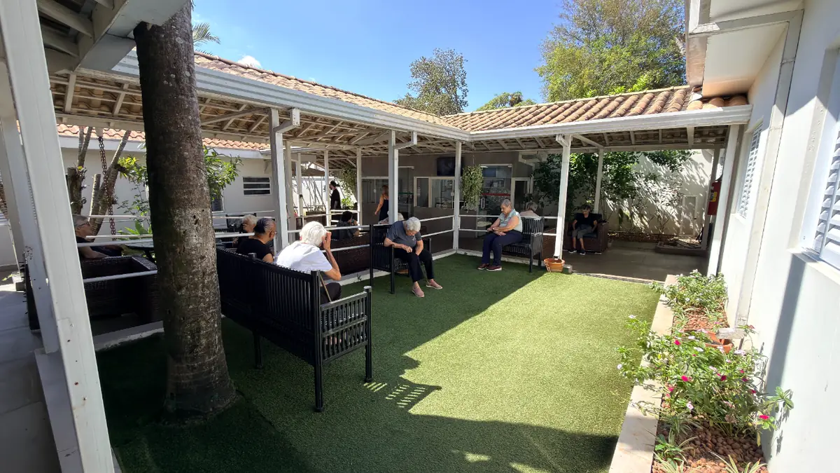 Jardim interno com gramado e bancos para residentes tomarem sol no Residencial Veneza