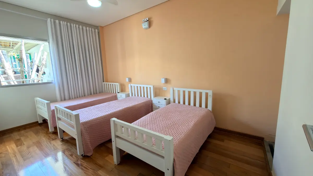 Quarto compartilhado com três camas e janela ampla no Residencial Veneza, casa de repouso em São Paulo