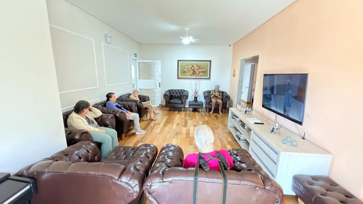 Sala de estar com TV, sofás e residentes reunidos no Residencial Veneza, casa de repouso em SP