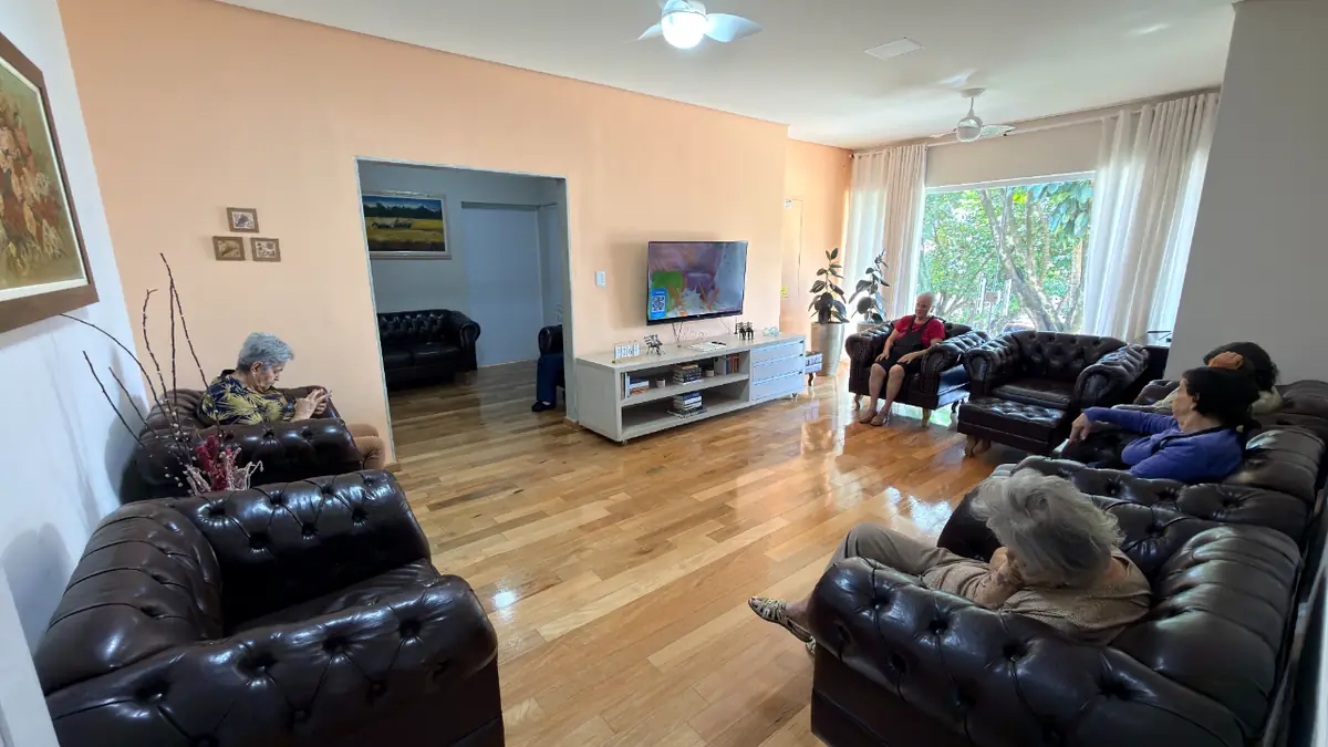 Sala de TV com sofás de couro e residentes assistindo televisão no Residencial Veneza