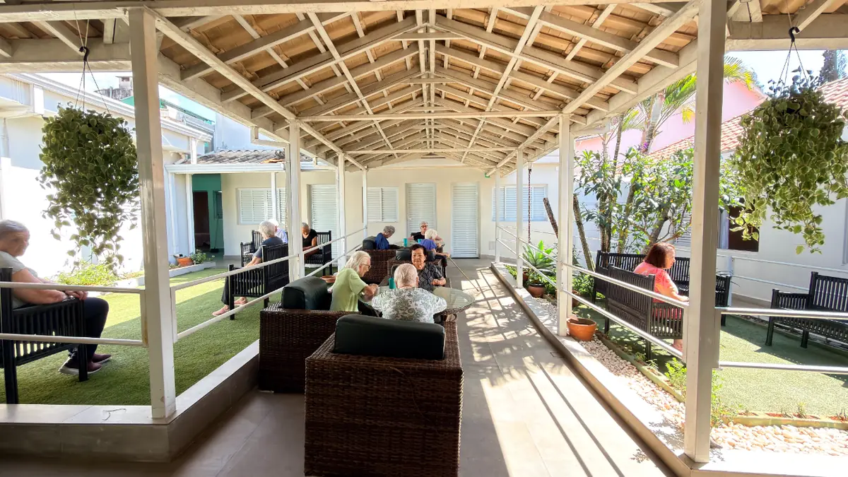 Varanda coberta com vasos suspensos e vista para o jardim no Residencial Veneza